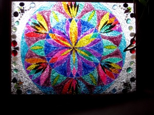 Photograph of a painted glass kaleidoscope-like piece with broken tempered glass on top of the painted work creating a sparkling effect.
